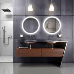 a bathroom with two sinks, mirrors and lights on the wall above it's counter