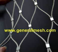 a hand holding a piece of wire that is attached to a black background with the words general mesh com on it