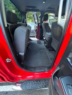 the interior of a red van with its doors open and seats folded down in front