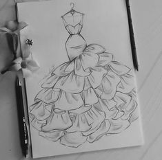 a drawing of a dress on paper next to markers