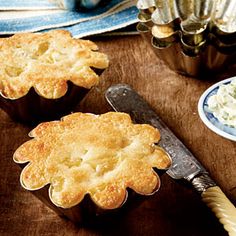 a wooden table topped with muffin tins filled with food next to a knife