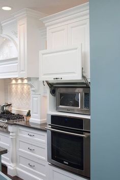 a kitchen with white cabinets and an appliance on the wall that says disappearing microwaves