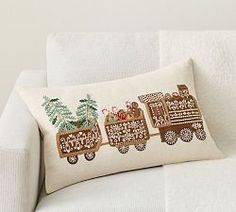 a white couch with a decorative pillow on it's back and an embroidered train