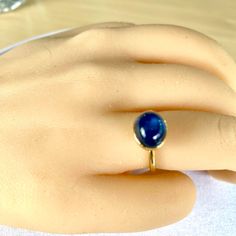 a close up of a person's hand wearing a ring with a blue stone