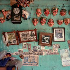 there are many masks on the wall with pictures and photos hanging from it's sides