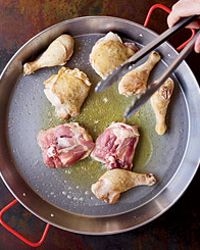 someone is cooking meat in a pan with tongs