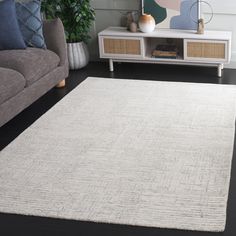 a living room area with a couch, coffee table and white rug on the floor