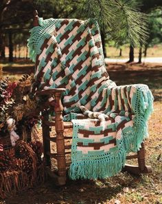 a crocheted blanket sitting on top of a chair next to a pine tree