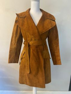 Channel the effortless style of the 1970s with this stunning vintage suede trench coat. This brown belted jacket features wide lapels and a rich, textured finish, offering a sophisticated yet timeless look. Perfect for both casual and formal occasions, this trench coat is a rare find that brings retro charm to any wardrobe. Its impeccable craftsmanship and classic design make it an essential piece for vintage fashion lovers. MEASUREMENTS:  Bust: 40" Waist: 38" CONDITION:  Excellent- Small discoloration in interior armpit. 🚦KEEP IN MIND -Please read the evaluation report of this vintage garment CAREFULLY 👀 before making the order (see referenced photos if applicable) Although we evaluate the item thoroughly and carefully, 1 or 2 imperfections may be missed and not stated in the descriptio Retro Belted Fall Outerwear, Retro Belted Outerwear For Fall, Retro Belted Outerwear For Work, Fall Suede Belted Outerwear, Vintage Long Sleeve Belted Outerwear, Vintage Belted Workwear Outerwear, Vintage Suede Outerwear For Fall, Vintage Belted Outerwear For Work, Vintage Suede Long Sleeve Outerwear