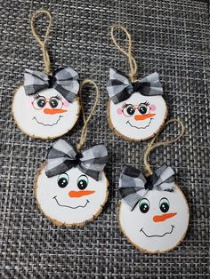 three snowman ornaments are hanging from twine strings on a gray fabric tablecloth