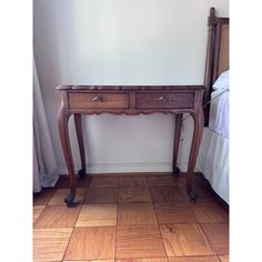 a wooden table with two drawers on top of it next to a bed and window