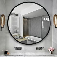 a bathroom with a large round mirror on the wall