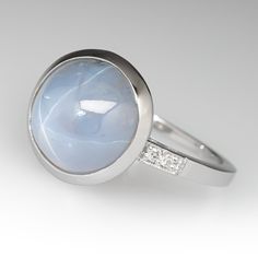 a white gold ring with a blue stone and diamonds on the side, set in 18k white gold