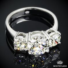 three stone diamond ring with reflection on black surface