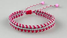 a red and white braided bracelet with pink beads on a gray background, close up