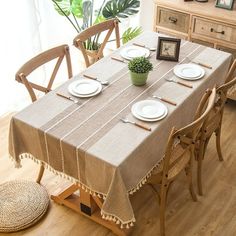 a dining room table with plates and place settings on it, in front of a potted plant