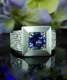 a ring with a blue diamond surrounded by purple flowers