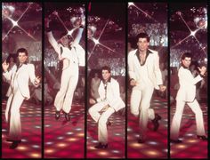 the man is dancing on stage with his hands in the air while wearing white suit and tie