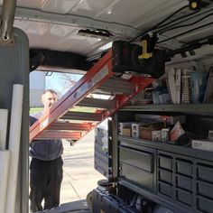 a man standing next to a ladder in the back of a truck