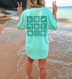 Design features a collection of teal squares with ocean elements cut out from them. Text reads "my heart belongs to the ocean." Comfort Colors Unisex Tee Info ∙ 100% ring-spun cotton ∙ Medium fabric (6.1 oz/yd² (206.8 g/m ∙ Relaxed fit, and can be sized up for a looser fit ∙ Sewn-in twill label ∙ Designs are Direct to Garment printed, resulting in a soft texture ∙ Please note color shades maybe slightly different to the pictures due to lighting and monitor settings **Because our shirts are print Cute Summer Shirt Designs, Turquoise Beach Tops, Turquoise Cotton Beach Tops, Turquoise Summer Tops For Beach Season, Summer Turquoise Tops For Beach Season, Summer Turquoise Top For Beach Season, Green Short Sleeve Beachwear Top, Casual Turquoise Top For Beach Season, Beachy Green Top With Relaxed Fit