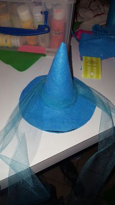 a blue hat sitting on top of a table next to some scissors and glues