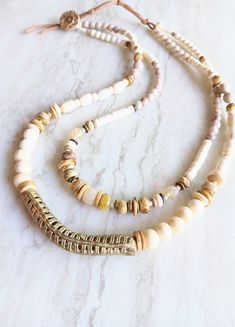 Bring elegance to every outfit you wear this with...amazing on everything linen, everything neutral or black. A standout piece! A variety of Picture Jasper, Natural Jasper, White Turquoise, Fossilized Coral, natural Howlite, bone beads, bone disks, mixed metal accents, and more. Focal is an Ashanti Ghana brass mesh tube bead with a slight elbow. Great texture and interest. Strung on Beadalon .018 7-strand Stainless Steel Bead Stringing wire-great strength and great flexibility. Unique shell and leather suede loop closure, extendable. Mixed media, shell, wood, and saucer beads. One-of-a-kind. The item/s pictured is the item you will receive. HavSolStudio on ETSY | Mixed media . Earthy elegance . Great texture . Beach inspired . Coastal calm . A little rustic . Worldly . Alluring . Recycled Bohemian Beaded Necklaces With Colorful Beads In Beige, Bohemian Beige Beaded Necklaces With Natural Stones, White Bohemian Beaded Necklaces For Layering, Earthy Beige Jewelry For Everyday Wear, Earthy Everyday Beige Jewelry, Brass Mesh, Fossilized Coral, Bone Beads, White Turquoise