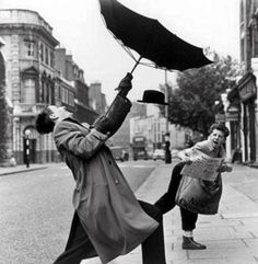 an old black and white photo of two people jumping in the air with an umbrella