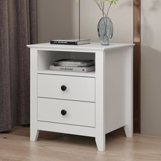 a white night stand with two drawers and a flower vase on the bottom shelf next to it