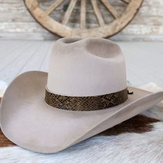 The Brown Snake Print hat band is a stylish leather accessory featuring a warm brown and black colored print on genuine leather. It measures 22.5" long and 1" wide. Adjustable leather ties ensure a perfect fit for almost any hat.     Length: 22.5 inches  Width: 1 inch  Adjustable Leather ties  Genuine Leather  *Hat not included*  CA Residents: Prop 65 Warning ↗️ Lv Hat Band, Luxury Adjustable Country Hat Band, Cheap Classic Hat Band For Spring, Silver Hats, Beaded Hat Bands, Kids Belt, Brown Snake, Beaded Hat, Leather Hat