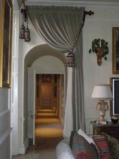 a living room filled with furniture next to a doorway covered in curtained drapes