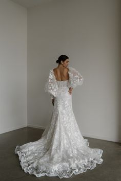 a woman in a white wedding dress standing against a wall