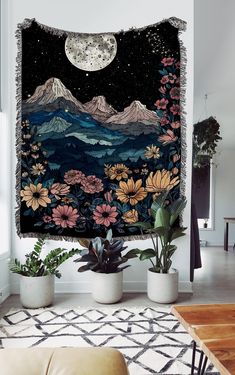 a tapestry hanging on the wall in a living room with potted plants and flowers