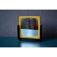 a small yellow and black object sitting on top of a blue table next to a gray wall