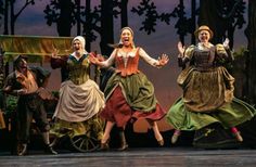 three women in dresses are dancing on stage