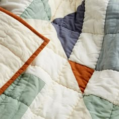 an orange, white and blue quilt on a bed