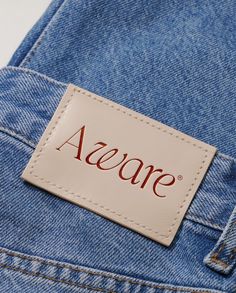 a name tag on the back of a pair of blue jean pants with red lettering