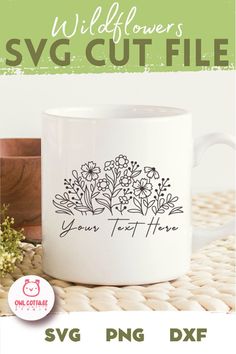 a white coffee mug sitting on top of a table next to a potted plant