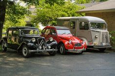 two old cars are parked next to each other in front of a trailer and bus