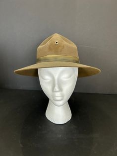 This vintage hat has a brown and olive green tint. Some call the Campaign Hat the 'Smokey the Bear' hat or the Forest Ranger hat, others the Drill Instructor hat. You also see this style mentioned in literature as a 'Baden-Powell' hat. This distinctive hat historically is associated with the campaigns of WWI or the American Boy Scouts (Baden-Powell is the founder).  Size 7 and about 5 inch Montana peak crown 3 inch flat, raw edge brim. Heavy and well made of 100% Wool with felt 4-pinch Montana p Vintage Flat Brim Fedora For Outdoor, Vintage Brown Flat Brim Adjustable Hat, Vintage Brown Adjustable Flat Brim Hat, Adjustable Vintage Brown Flat Brim Hat, Vintage Felt Hat With Curved Brim For Outdoor, Brown Military Brimmed Hat, Military Style Brown Cap, Brown Military Style Cap, Military Style Brown Hat With Curved Brim