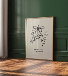 a framed poster on the floor in front of a green wall with an image of flowers