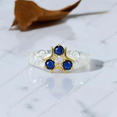 a gold ring with blue and white stones on the side, sitting on a marble surface