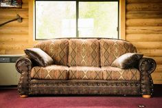 a couch sitting in front of a window on top of a red carpeted floor