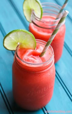 two glasses filled with watermelon and limeade on top of a blue table