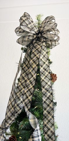 a christmas tree decorated with plaid ribbon and pine cones