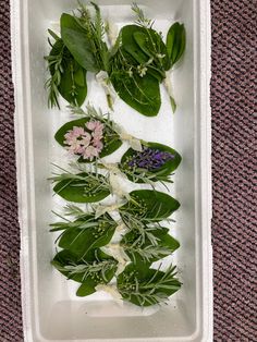 some flowers and leaves in a white container