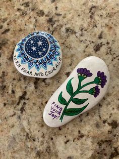 two painted rocks sitting on top of a counter