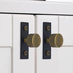 two black and gold knobs on white cabinets