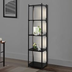 a black shelving unit in a living room next to a table with flowers on it