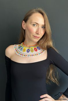 a woman wearing a colorful beaded necklace and black top with her hands on her hips