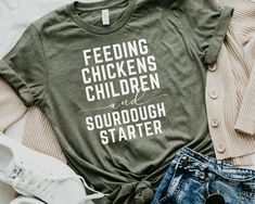 Celebrate your love for sourdough, chickens and your children with this cozy t-shirt, perfect for homestead mamas and chicken lovers. This funny and faith-inspired tee makes an ideal Mother's Day gift for any bread-baking enthusiast or homeschool mama. HOW TO ORDER - Visit photos for sizing and measurements - Select size and color from dropdown menu - Add customization to box if required - Add to cart & proceed to checkout * If you are ordering multiple, then go back to listing and perform steps Sourdough Shirt, Homestead Gifts, Silouette Cameo, Cricut Shirts, Wardrobe Makeover, Chicken Decor, Chicken Shirts, Chicken Lovers, Vinyl Shirts